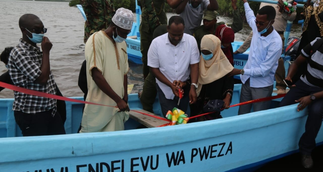 Group of people cutting ribbon at the opening of a fishing boat.