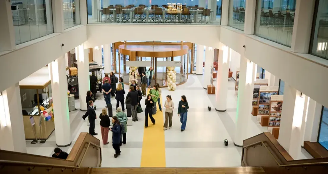 People gathered in a modern space with yellow floor and stairway.