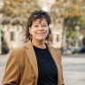 Woman with medium-length brown hair, enjoying a sunny day in The Hague.