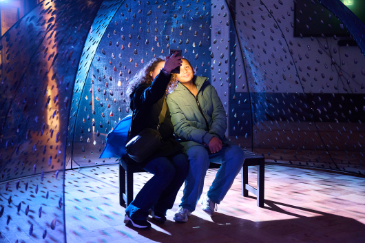 Two people posing together in a dimly lit space.