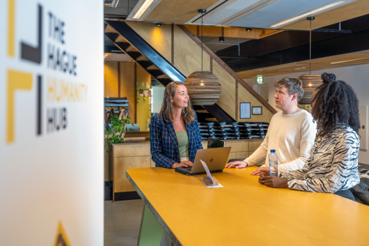 Three people discussing ideas with a laptop in a modern space