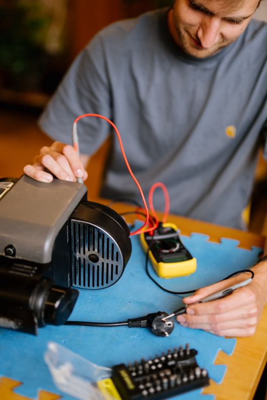 A boy is examining an electrical device with tools.