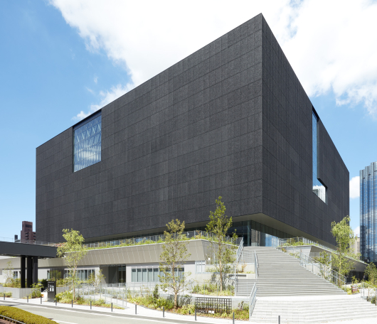A modern building with a flat black façade and steps