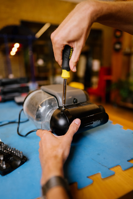 A hand using a screwdriver to repair a device.