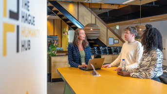 Three people discussing ideas with a laptop in a modern space