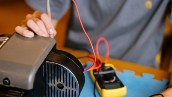 A boy is examining an electrical device with tools.