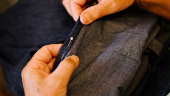 A woman's hand holds a piece of fabric with a pin