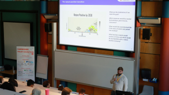 A speaker presents on nature-positive economy in a classroom.