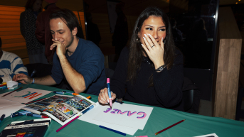 Two people engaging in a creative activity, laughing and drawing.