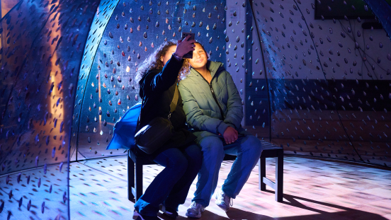 Two people posing together in a dimly lit space.