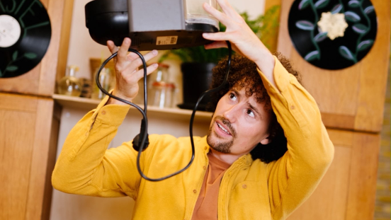 A man holds a kitchen appliance above his head.