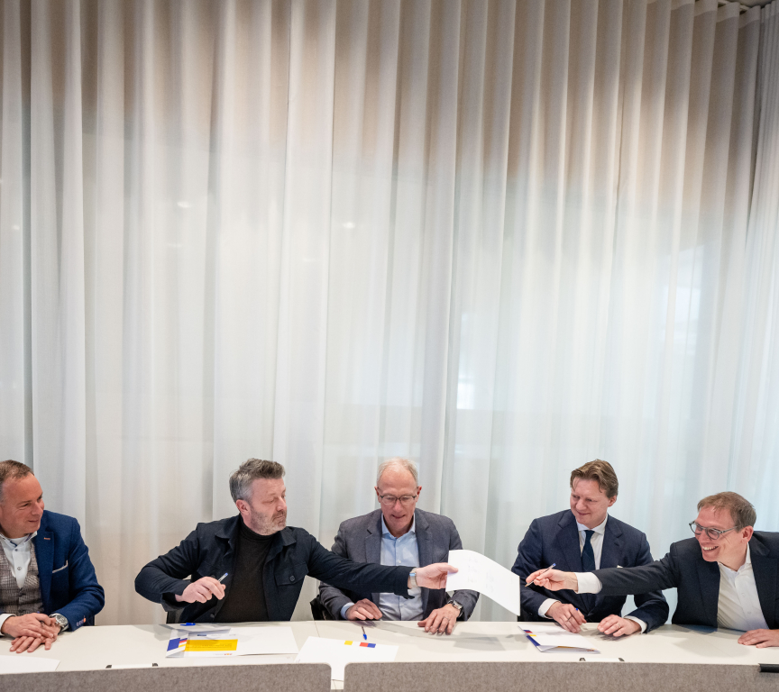 Five men jointly signing documents at a table