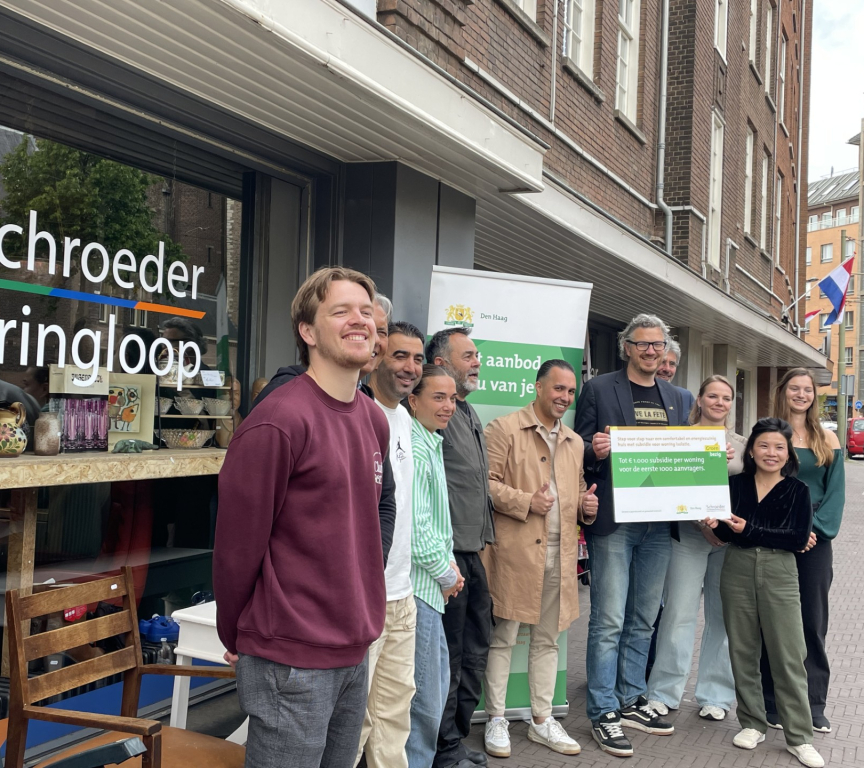 A group of people posing in front of Schroeder Kringloop in The Hague.