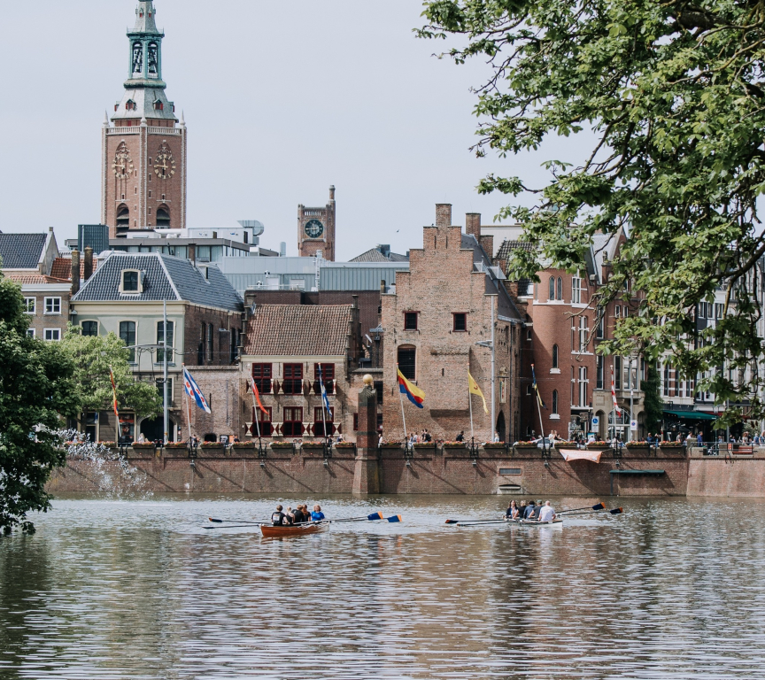 People rowing on the water with the Binnenhof in the background