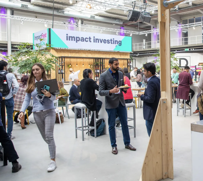 Picture taken at ImpactFest 2022 with a large sign in the background stating 'Impact Investing'.