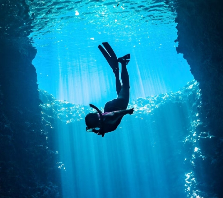 A diver exploring underwater with rays of light.