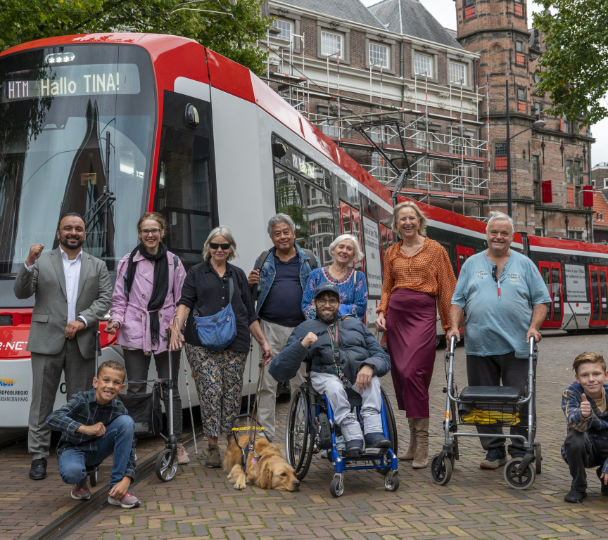 A diverse group of people posing in front of a tram in The Hague.