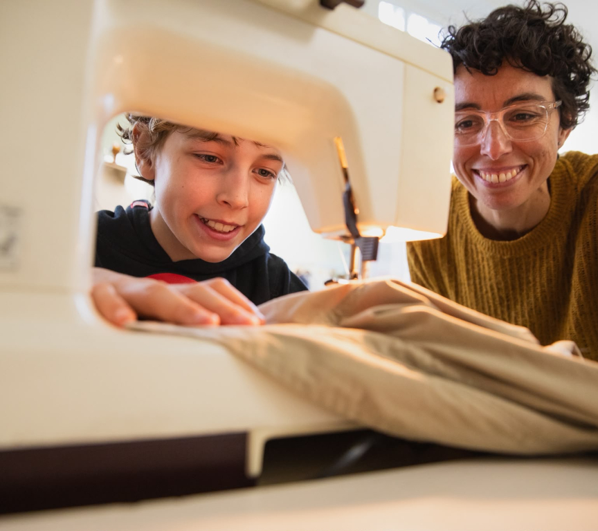 A child and an adult working together at a sewing machine.