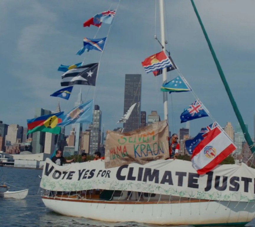 A sailing boat with flags, participants advocating for climate justice.