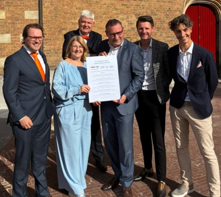 Six people posing with a document in The Hague.