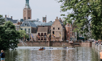 People rowing on the water with the Binnenhof in the background