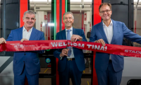Three men unveiling a red ribbon for a new tram in The Hague.