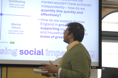 Man giving a presentation with graphs displayed on screen.