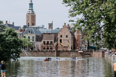 People rowing on the water with the Binnenhof in the background