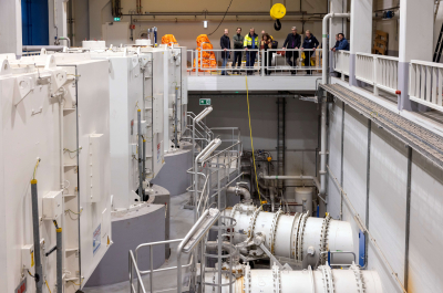 A modern technical space with equipment and visitors on the upper floor.