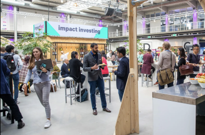 Picture taken at ImpactFest 2022 with a large sign in the background stating 'Impact Investing'.