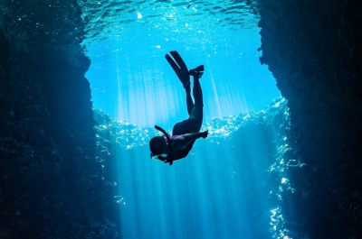 A diver exploring underwater with rays of light.