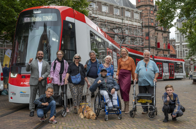 A diverse group of people posing in front of a tram in The Hague.