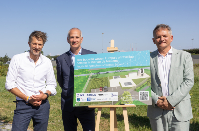 Three men stand next to an illustration of the future optical ground station