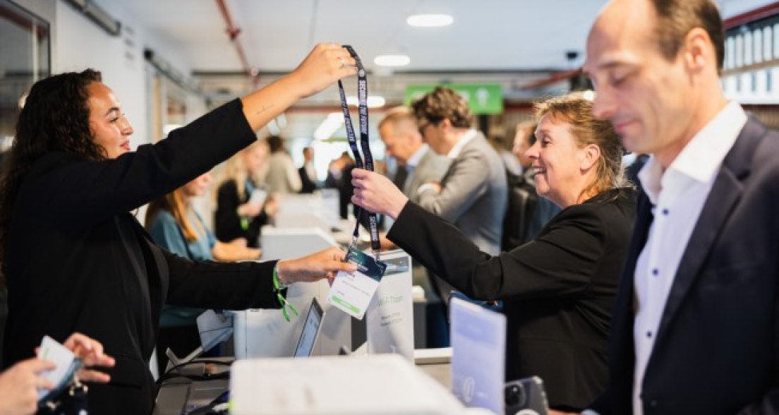 People registering at an event, badges being handed out.