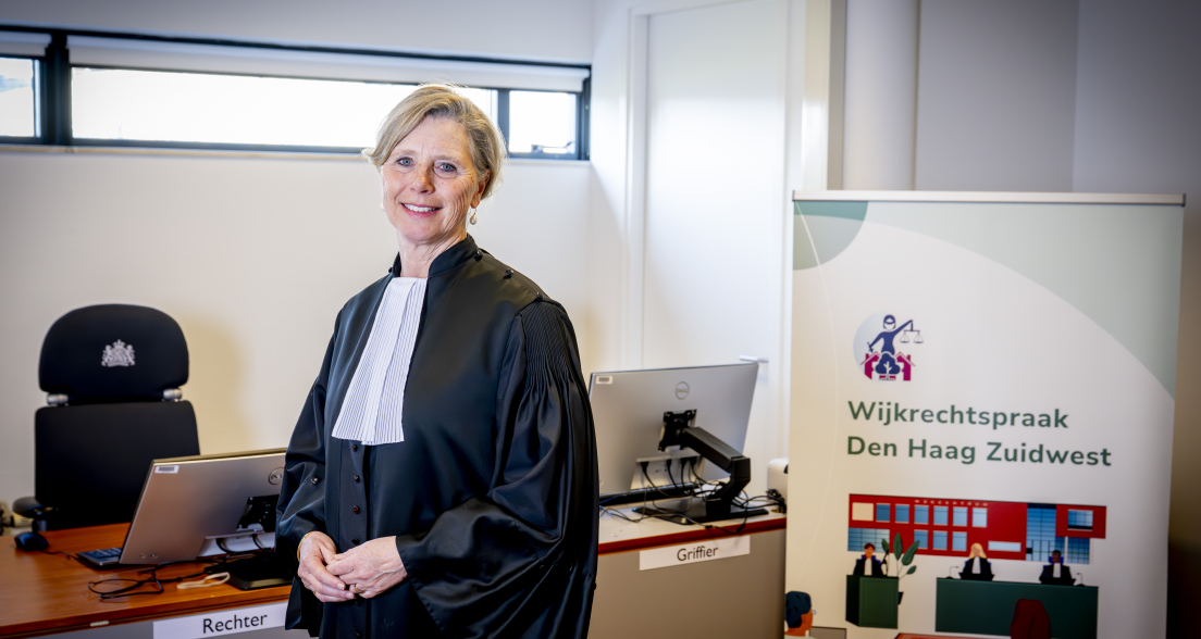 Judge Robine de Lange in official robes at the Wijkrechtspraak Den Haag Zuidwest courtroom, a community court initiative in The Hague improving access to justice for local residents.