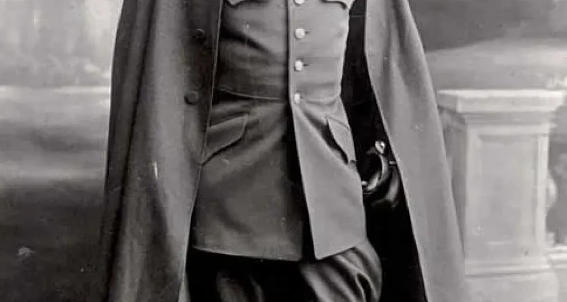 Full-length portrait of Major Lodewijk Thomson in formal military uniform with high boots, decorated medals, and a long cape. He stands in a studio setting with a painted backdrop, exuding authority and poise.
