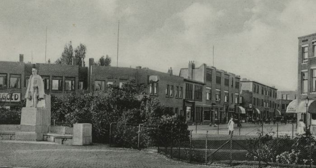 Historic black-and-white photo of Thomsonplein in The Hague, circa 1935, featuring the statue of Major Lodewijk Thomson in the foreground and a view of surrounding residential buildings and shops.