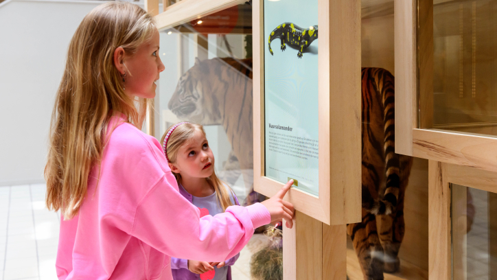 Twee kinderen kijken naar een uithangbord van een vuursalamander.