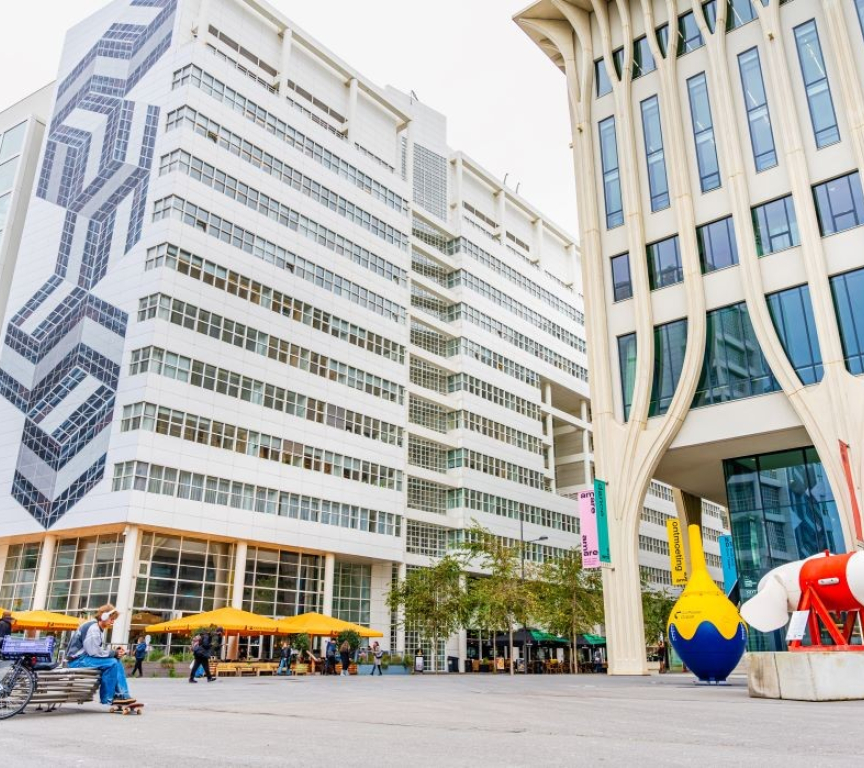 Een modern gebouw met kunstwerken en zitruimte buiten.