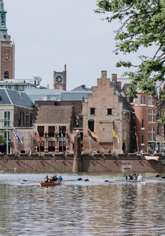 People rowing on the water with the Binnenhof in the background