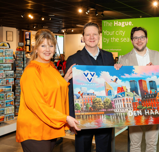 Four people are holding a gift card for Den Haag.