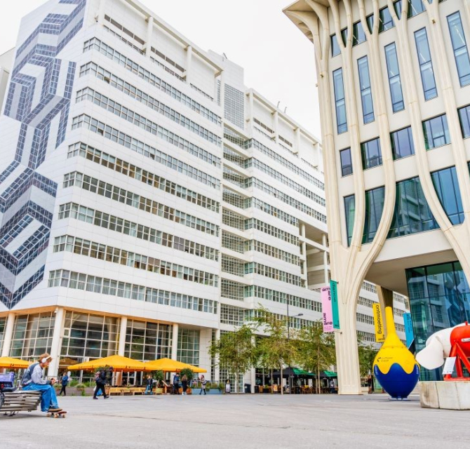 Een modern gebouw met kunstwerken en zitruimte buiten.