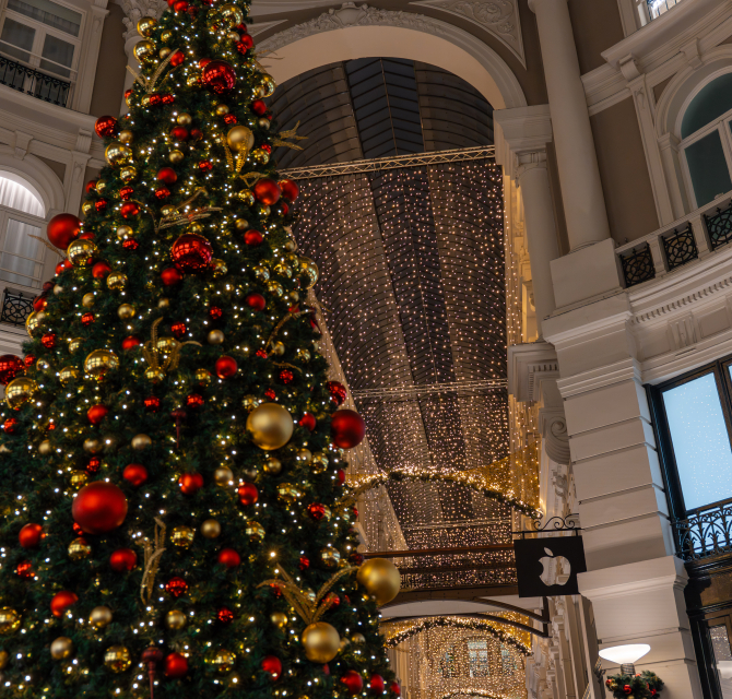 Grote kerstboom versierd met rode en gouden ornamenten.