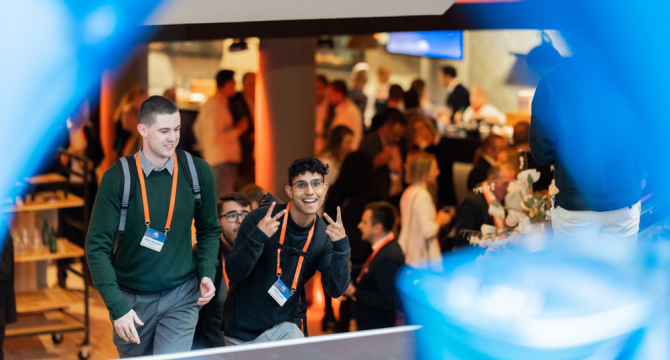 Twee jongeren glimlachen en poseren op een evenement.