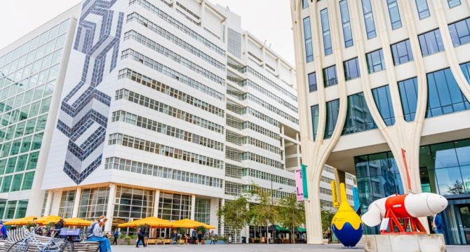 Een modern gebouw met kunstwerken en zitruimte buiten.