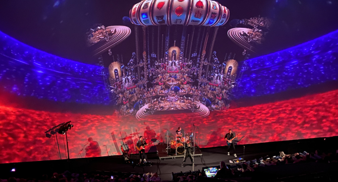 Een liveband speelt op een podium met kleurrijke projecties op de achtergrond.