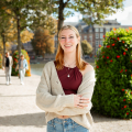 Een vrouw met lang haar glimlacht in een park in Den Haag.