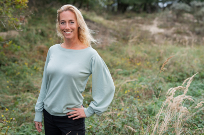 Woman with blonde hair in a green sweater, standing in the grass
