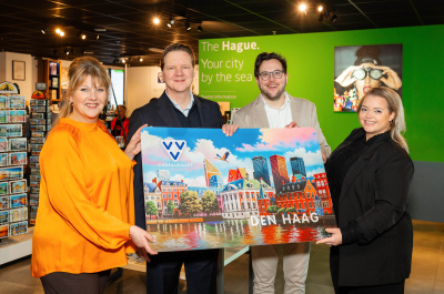 Four people are holding a gift card for Den Haag.