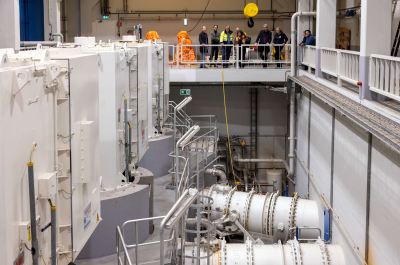 Technicians in a machinery room with large equipment.